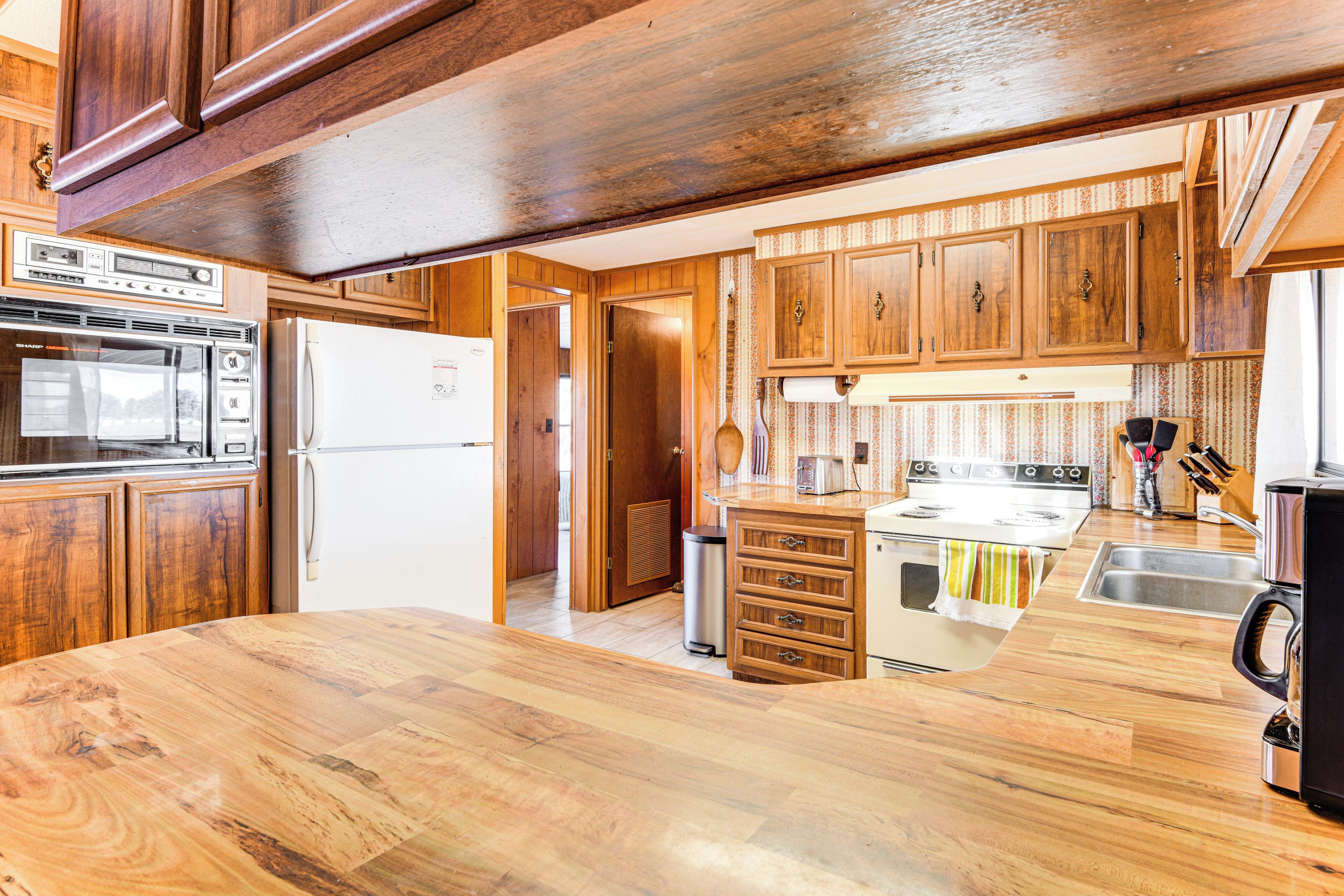A kitchen with wooden cabinets, a stove, a refrigerator, and a sink.