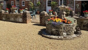 A traditional brick building with a stone courtyard, potted plants, and a stone fountain. - Cosy converted barn in rural location with views of the surrounding countryside. (Newport)