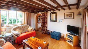 A cozy living room with a sofa, a wooden coffee table, a television, and a fireplace. - Cosy converted barn in rural location with views of the surrounding countryside. (Newport)