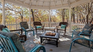 A covered outdoor seating area with wicker chairs and a fire pit. - Six Suites with Hot Tubs, Private Jacuzzi Baths, Wooded Garden and Lake Access with Boat Slip (Osage Beach)