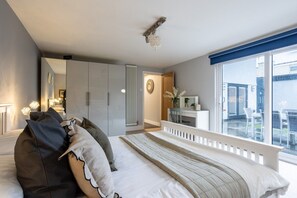 A bedroom with a bed, a dresser, a radiator, a window with a view, and a ceiling light fixture.