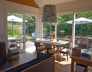 A spacious patio area with a dining table, chairs, and umbrellas, connected to a room with a sofa and a heater. - Vacation home MV8 (Egmond-Binnen)