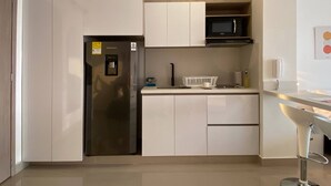 A modern kitchen with white cabinets, a stainless steel refrigerator, a microwave, and a bar stool. - w Divine Loft w Ocean View in Crespo (Cartagena)
