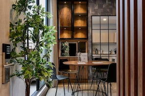 A modern dining area with a wooden table and black chairs, a potted plant, and a view of the kitchen area. - w Elegant Loft w Terrace in Santa Barbara (Bogotá)