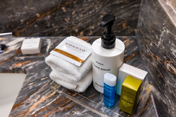 A bathroom counter with toiletries including a bottle of shampoo, a towel, and a soap dispenser.