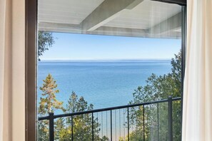 A balcony with a view of the sea and trees.