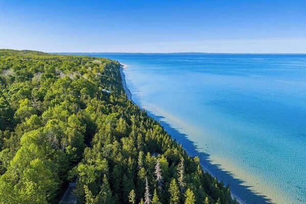 A coastal forested area with a clear view of the ocean.