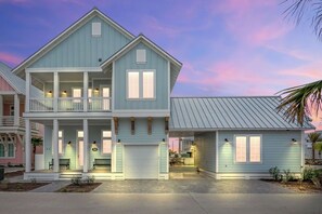 A two-story house with a balcony, a garage, and a covered porch. - New home in CS South with access to 20+ resort like amenities (Port Aransas)