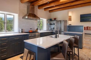 A modern kitchen with dark cabinetry, a central island, and a view of the outdoors.