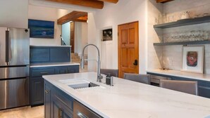 A modern kitchen with a marble island, stainless steel appliances, and wooden beams. - Sunset Mountain Ranch - 5 Bedroom (Santa Fe)