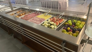 Een buffet met diverse gerechten, zoals vlees, fruit en groenten.