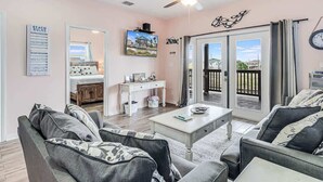 A living room with a sofa, coffee table, and a TV. There is a balcony with a view. - Twin Palms 2.0 (Rockport)