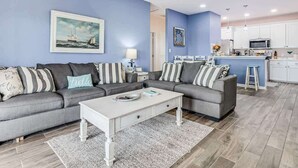 A living room with two grey sofas, a white coffee table, and a kitchen in the background. - Twin Palms 2.0 (Rockport)