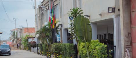A street view with buildings, a parked car, and a flag.