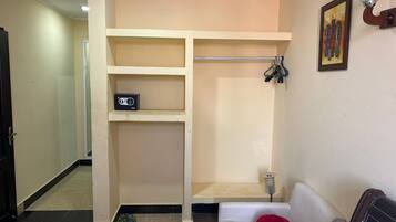Una habitación con un sofá blanco, un peluche rojo, un estante con una radio y un cuadro en la pared.
