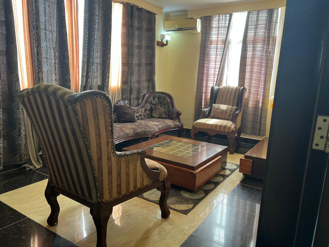 Una sala de estar con sillones a rayas, un sofá y una mesa de centro.