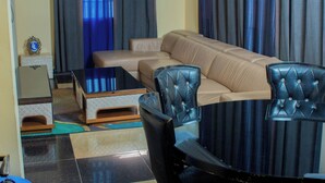 A living room with a beige sofa, a black glass coffee table, and two black upholstered chairs. - HOTEL LLAELL (Luanda)