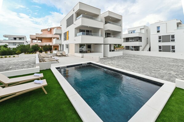 A modern residential building with a swimming pool, outdoor seating, and a well-maintained lawn. - Break A4 one-bedroom apartment (Novalja)