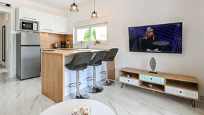 Une cuisine moderne dotée d’un îlot central, de tabourets de bar, d’un téléviseur et d’une console en bois.