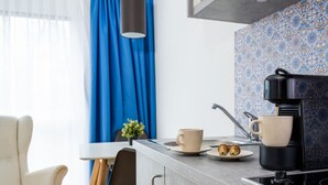 A modern kitchen with a coffee maker, a cup, and a plate with two eggs. - Arbio I Disability Accessible Studio (Graz)