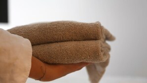 A hand holding a folded brown towel. - Arbio I Cozy Studio Balcony WKO Steiermark Graz (Graz)
