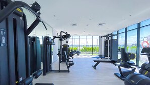 Un gimnasio moderno con diverso equipamiento de ejercicio, amplias ventanas y vistas al exterior.