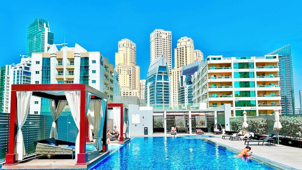 A swimming pool with a cityscape in the background. - Balcony Bliss: Cozy Studio With Marina Views (Dubai)