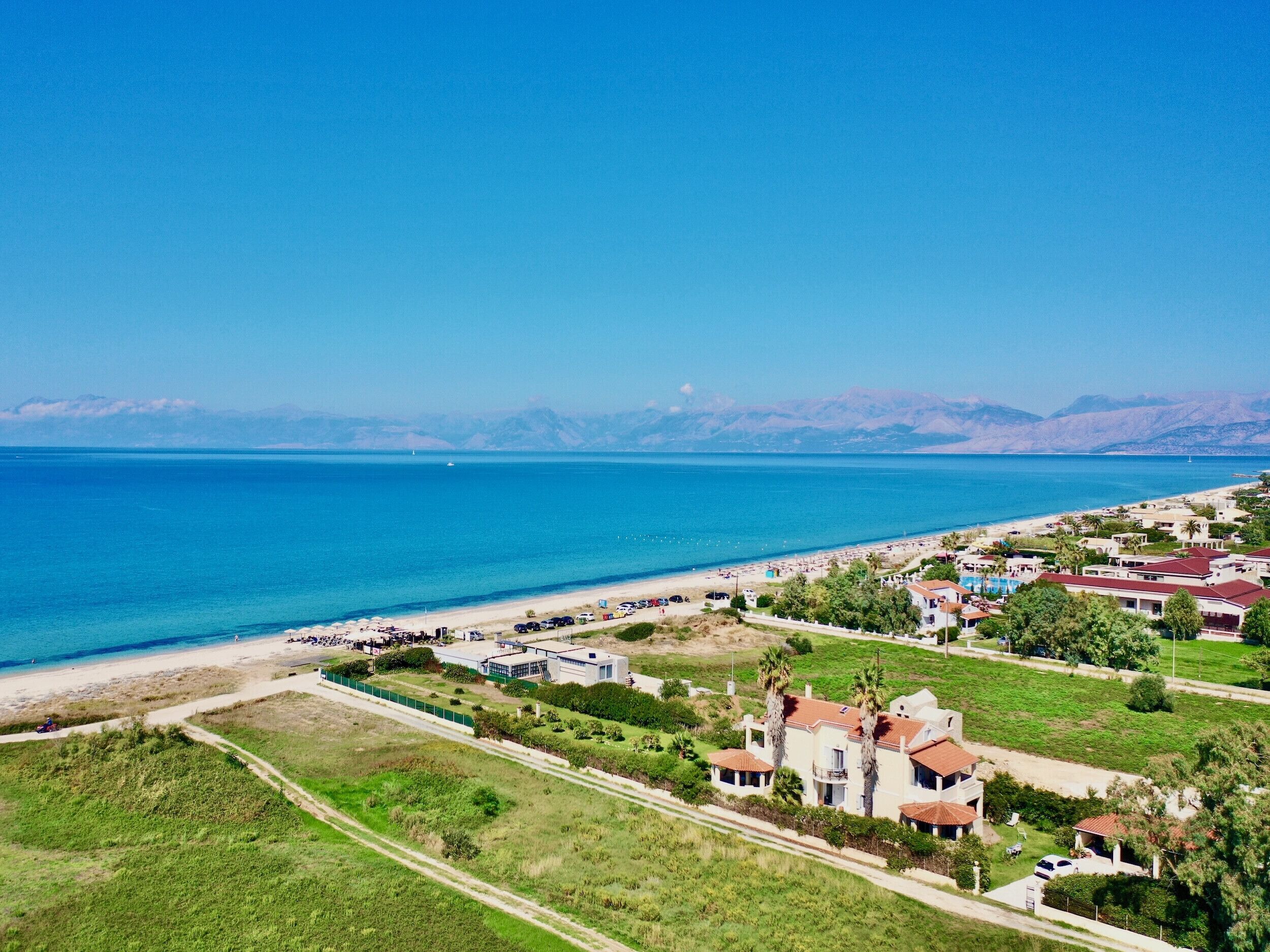 Zona residencial costera con casas, una playa y un mar azul cristalino.