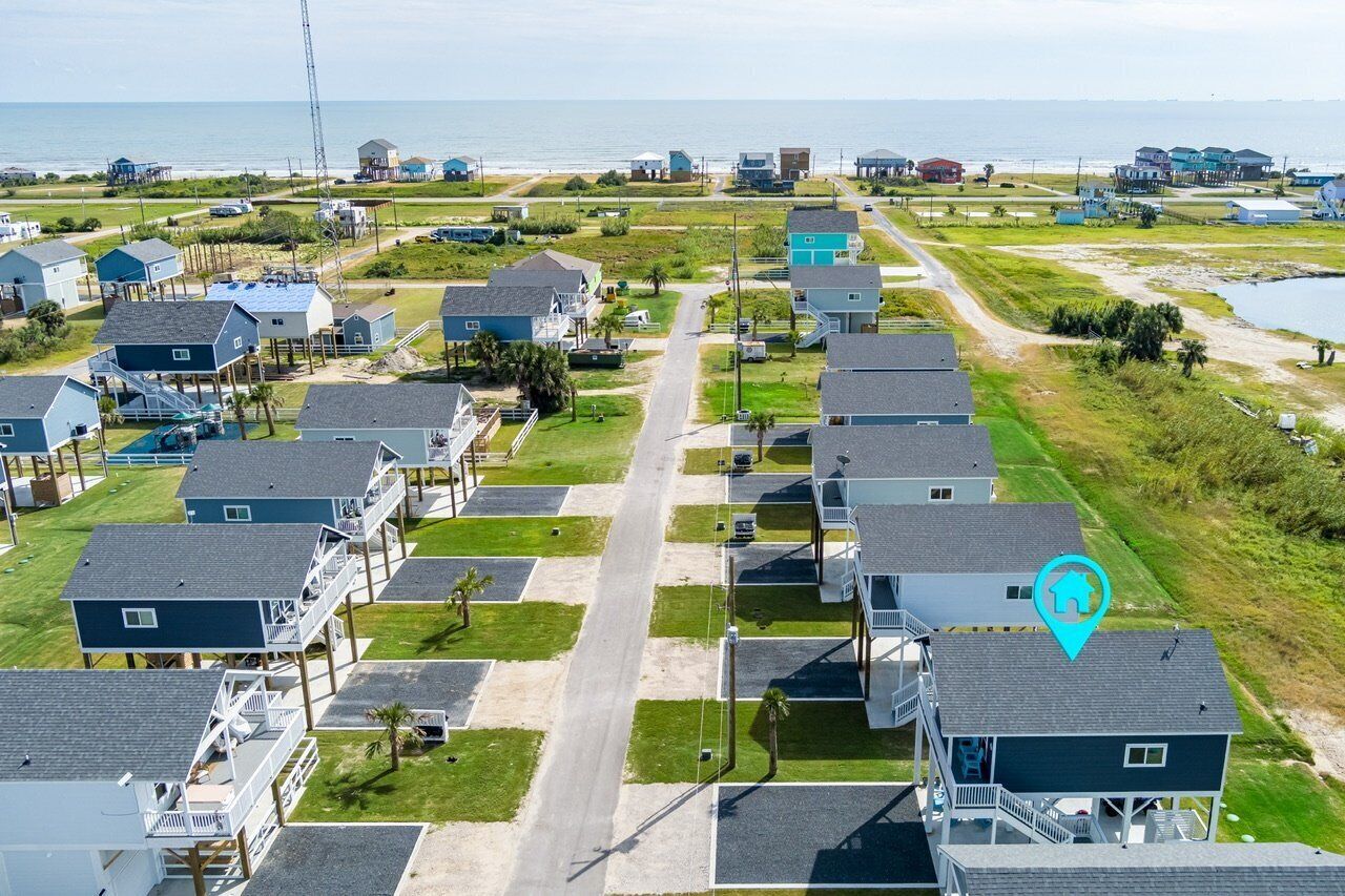A coastal residential area with multiple two-story houses, some with balconies, and a clear view of the ocean.