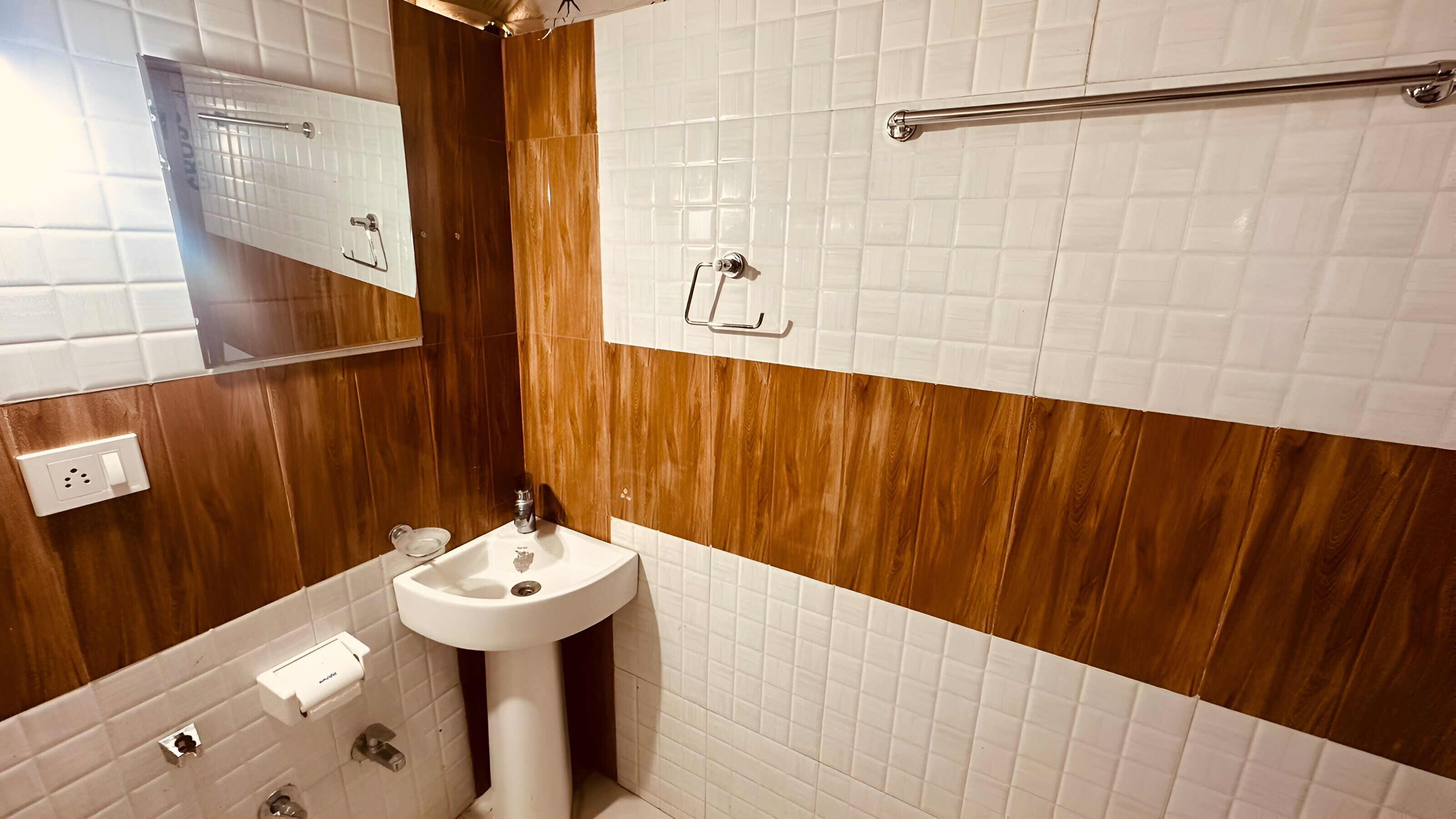 A bathroom with a wooden vanity, a white sink, and a mirror.