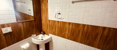 A bathroom with a wooden vanity, a white sink, and a mirror.