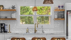 Une cuisine moderne avec une grande fenêtre, des chaises en bois et une machine à café.