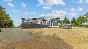Une maison à deux étages avec un grand garage et un espace extérieur aménagé avec des sièges.