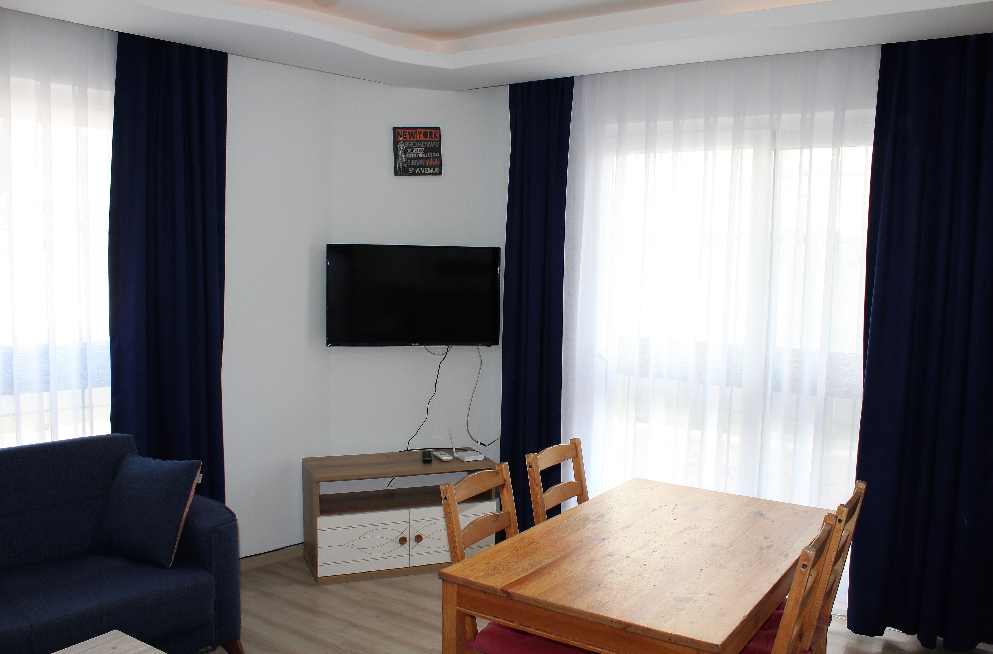 A living room with a TV mounted on the wall, a wooden table, and a blue sofa.