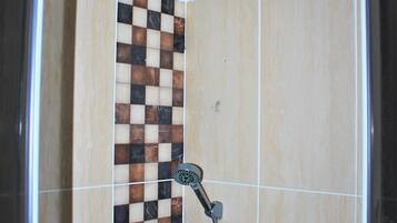 A shower with a checkered tile design, a handheld showerhead, and a wall-mounted faucet.