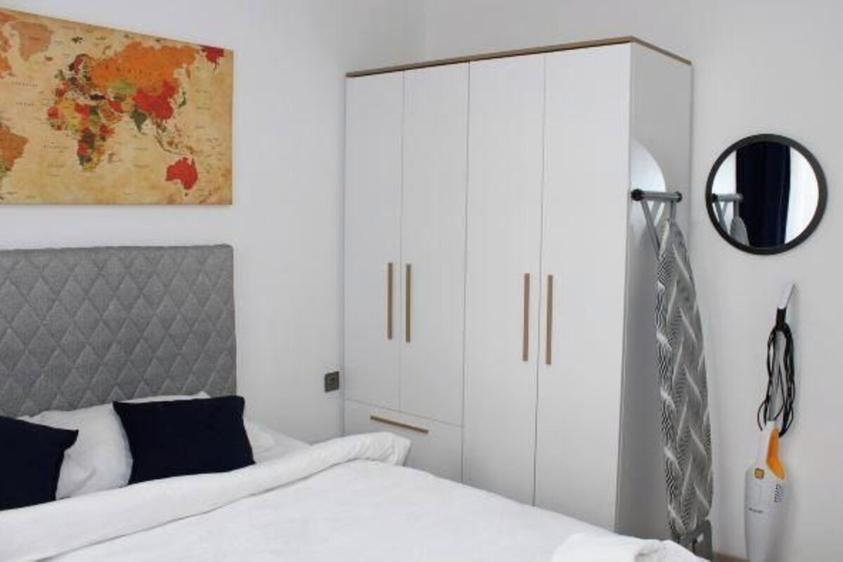 A bedroom with a bed, a wardrobe, a map on the wall, and a hairdryer.