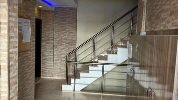 Ein modernes Interieur mit einer Marmortreppe, Metallgeländern und einem Holzkabinett.