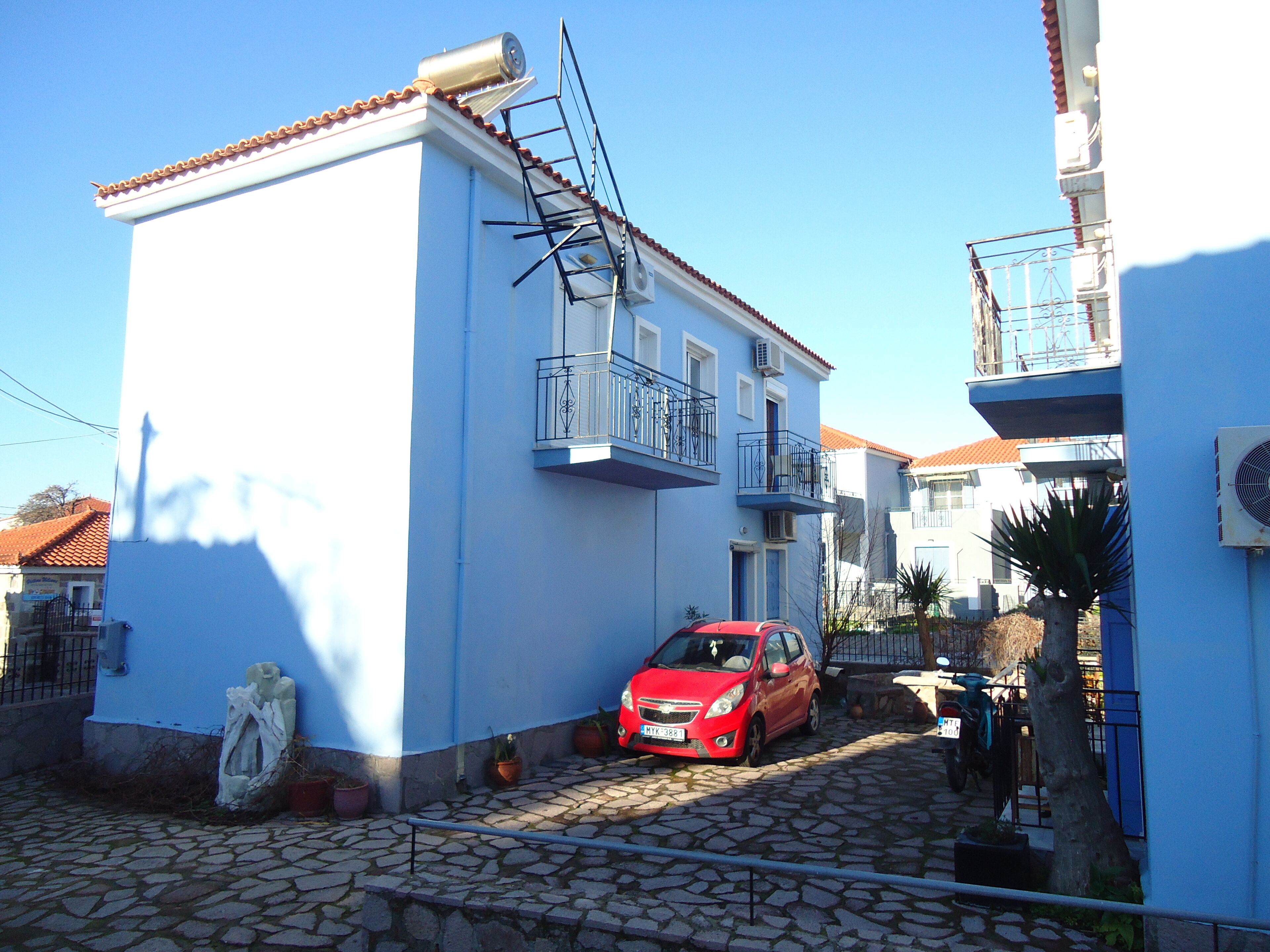 Una estrecha calle adoquinada con un coche rojo estacionado al lado.
