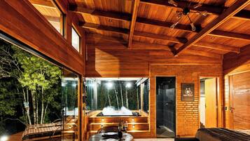 A wooden interior with a sauna, glass walls, and a view of trees outside.