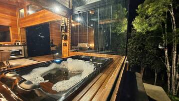 Relax in a spacious room with a large hot tub, wooden paneling, and a kitchenette with oven and microwave.