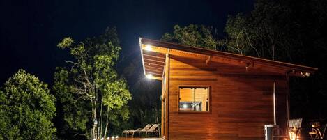 Une cabane en bois avec une seule fenêtre visible, entourée d’arbres.