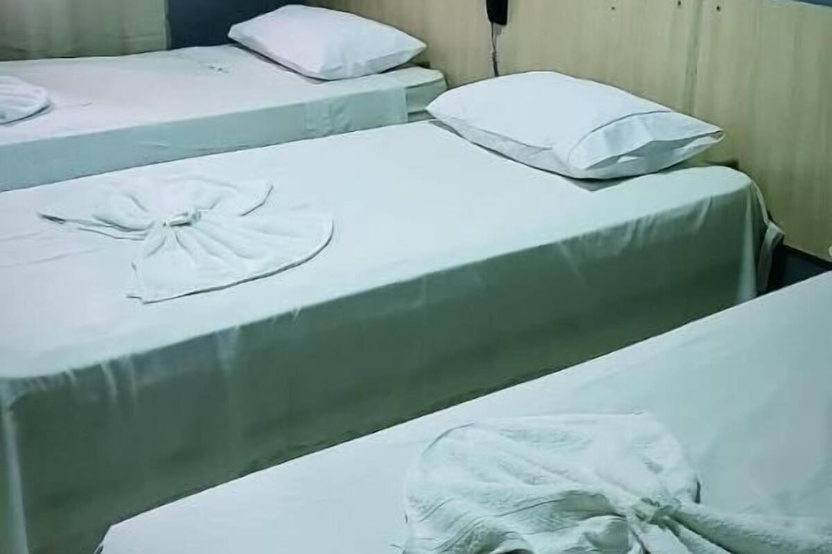 Habitación de hotel con dos camas individuales, un teléfono en la mesita de noche y una ventana con cortinas.