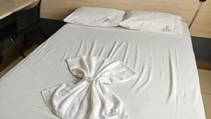 Una habitación de hotel con una cama bien tendida, un cabecero de madera, un escritorio y una silla.
