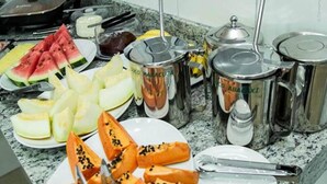 Un bufé con diversas frutas y platos, entre ellos sandía, melón y papaya.
