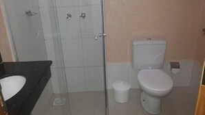 Un baño con cabina de ducha de vidrio, inodoro y lavamanos.