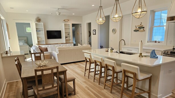 A modern kitchen with a central island, wooden dining table, and bar stools. - The Seashelle is a New Four Bedroom, Four ½ Bath home with a Pool. (Fripp Island)