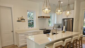A modern kitchen with a large island, white cabinetry, and pendant lighting. - The Seashelle is a New Four Bedroom, Four ½ Bath home with a Pool. (Fripp Island)