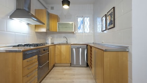 A modern kitchen with wooden cabinets, stainless steel appliances, and a dishwasher. - Stay U-nique Apartment Gran Via IV (Barcelona)