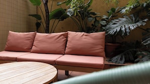 A cozy outdoor seating area with a cushioned bench and a round wooden table. - Stay U-nique Apartment Gran Via IV (Barcelona)