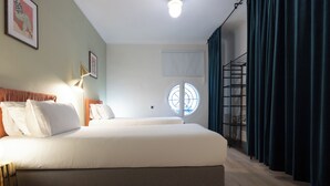 A modern hotel room with a large bed, a round window, and a view of the sky. - Stay U-nique Apartment Gran Via IV (Barcelona)